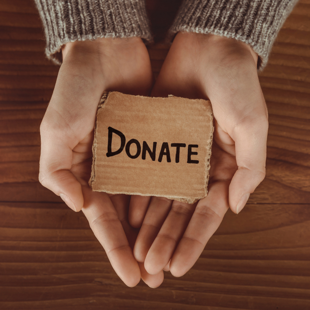 Hands holding a sign that says Donate